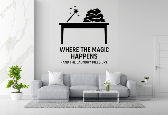 a living room with a gray sofa, a coffee table, and a potted plant. Above the sofa, there is a wall decal that says 