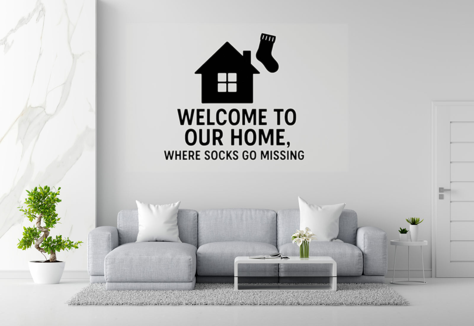 a living room with a gray sofa, a coffee table, and a potted plant. Above the sofa, there is a wall decoration that says 