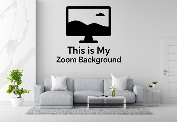 a living room with a gray sofa, a coffee table, and a potted plant. Above the sofa, there is a wall decal that says 