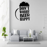 a living room with a gray sofa, a coffee table, and a potted plant. Above the sofa, there is a wall decal that says "DON'T WORRY BEER HAPPY".