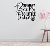 a wall with a wall decal that says "So many beers so little time" along with a beer mug icon. Next to the wall, there is a small table with a vase of pink flowers.
