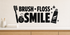 Black Brush Floss Smile bathroom wall decal with toothbrush, floss, toothpaste, and sparkles above a light oak vanity.