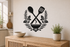 Exact botanical kitchen utensil black vinyl wall decal with crossed spoon, spatula, herb wreath, steaming bowl, and leaf ornament above a pale oak console.
