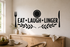 Exact EAT LAUGH LINGER matte black dining wall decal in a bright breakfast nook with plate, utensils, and olive branches.