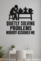 Quietly Solving Problems Nobody Assigned Me black vinyl wall decal shown applied to a smooth interior wall