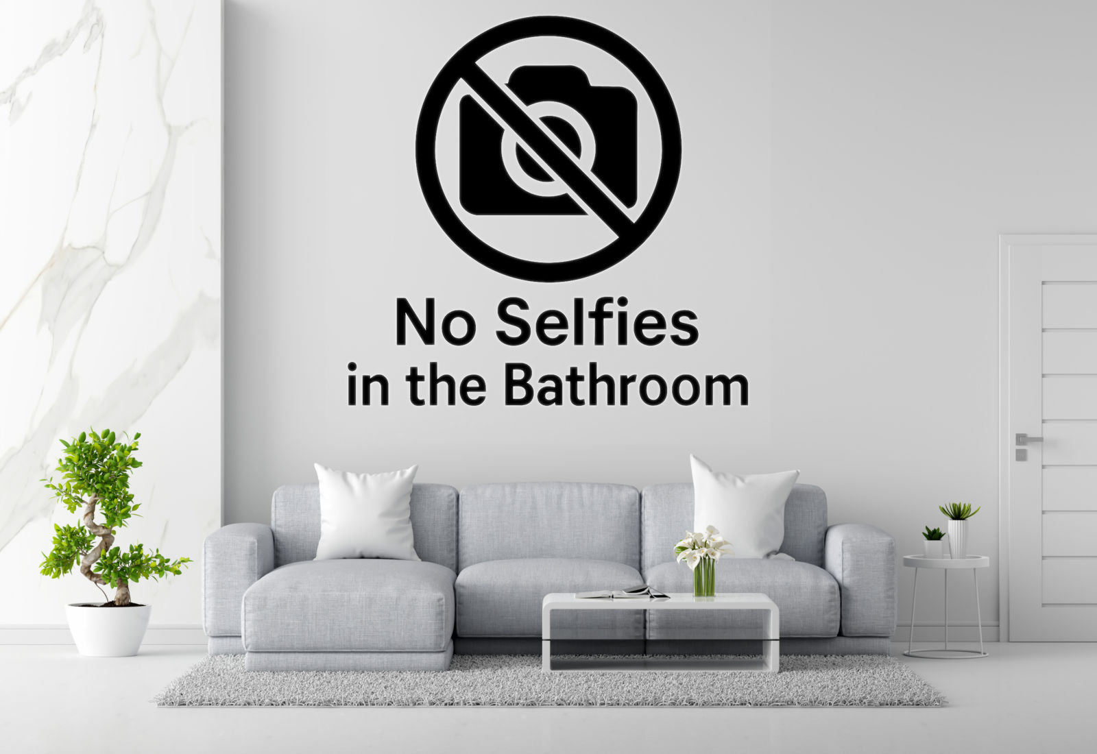 a living room with a gray sofa, a coffee table, and a potted plant. Above the sofa, there is a sign that says 