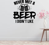 a wall with a humorous text that reads "NEVER MET A BEER I DIDN'T LIKE" along with a graphic of two beer mugs. There is also a small table with a vase of pink flowers in the background.