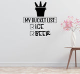 a wall with a humorous text that reads "MY BUCKET LIST: ICE, BEER" along with a silhouette of a bucket with ice and beer bottles. There is also a vase of pink flowers placed on a table in the background.