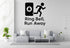 a living room with a gray sofa, a coffee table, and a potted plant. Above the sofa, there is a wall decal that says "Ring Bell, Run Away".