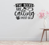 a wall decal with the text "THE BEERS ARE CALLING I MUST GO" along with a beer mug and a bottle, all in a black and white design.