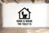a wall with a black and white graphic of a house with a toilet inside, accompanied by the text "HOME IS WHERE THE TOILET IS" below the graphic.