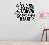 a wall with a black and white text quote that says "Beer never broke my heart". There is also a vase of pink flowers placed on a table next to the wall.