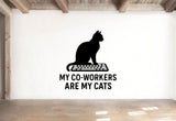 a wall with a black silhouette of a cat sitting on a computer keyboard, accompanied by the text "MY CO-WORKERS ARE MY CATS" below the image.